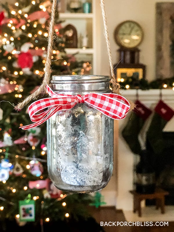 Mini mason jar with a silvery mottled mercury glass finish, tied with twine and lit by a small votive inside
